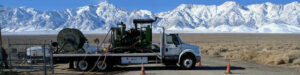 Welljet truck and equipment in front of snow-covered hills.