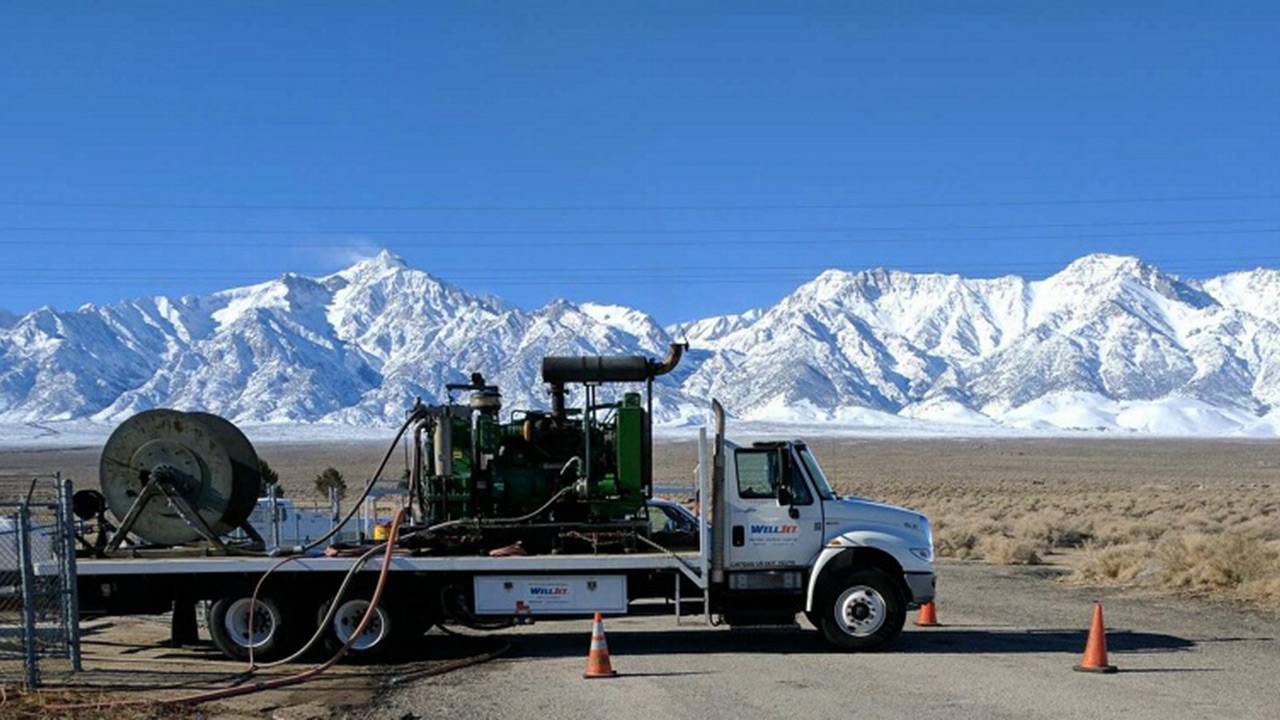 WellJet trucks and equipment in the field, snow-covered mountains in background.